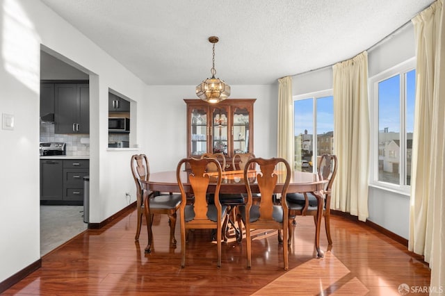 dining area featuring dark wood-type flooring, baseboards, and a textured ceiling