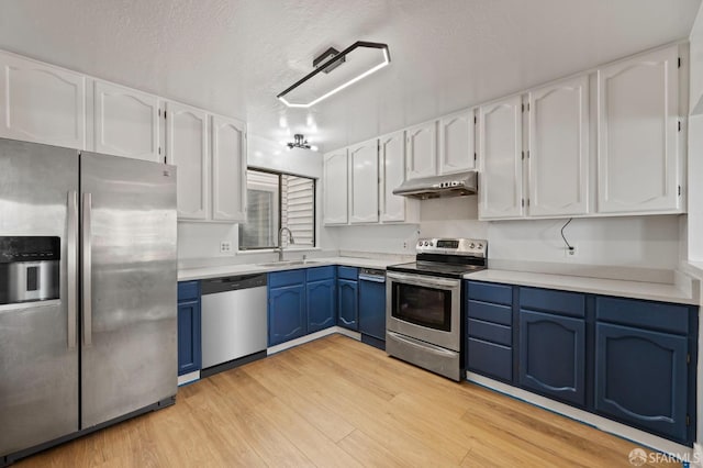 kitchen with appliances with stainless steel finishes, blue cabinets, a sink, and under cabinet range hood