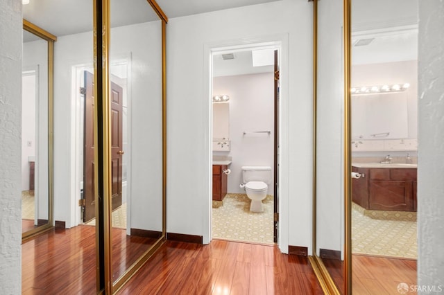 hallway featuring a sink and wood finished floors