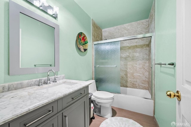 bathroom featuring toilet, shower / bath combination with glass door, and vanity