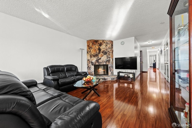 living room with a textured ceiling, wood finished floors, and a fireplace