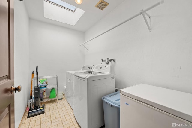 clothes washing area featuring visible vents, a skylight, separate washer and dryer, and laundry area