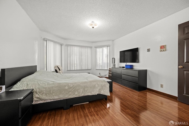 bedroom featuring a textured ceiling, baseboards, and wood finished floors