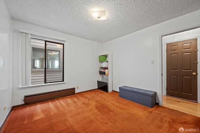 carpeted empty room with a baseboard radiator and a textured ceiling