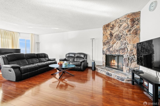 living area with a textured ceiling, wood finished floors, and a fireplace