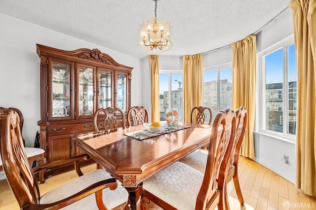 dining space with a chandelier, light wood finished floors, and a textured ceiling