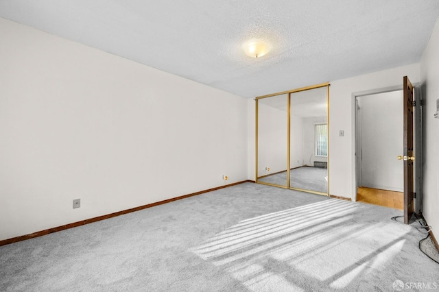 unfurnished bedroom featuring carpet floors, baseboards, a closet, and a textured ceiling