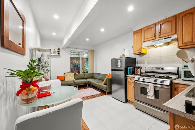 kitchen with recessed lighting, open floor plan, backsplash, under cabinet range hood, and appliances with stainless steel finishes