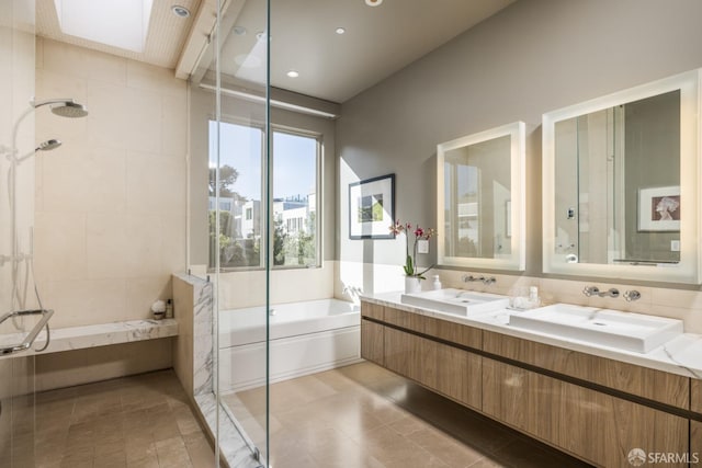 full bath featuring a bath, a tile shower, and a sink