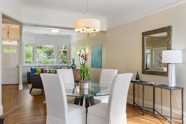 dining room with baseboards, an inviting chandelier, crown molding, and wood finished floors