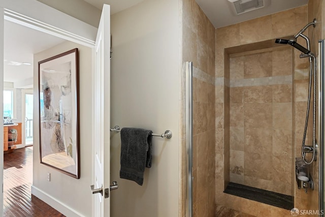 full bath with a stall shower, baseboards, visible vents, and wood finished floors