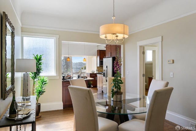 dining space featuring baseboards, a healthy amount of sunlight, a chandelier, and light wood-type flooring