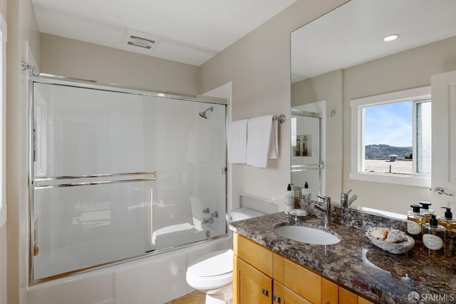 full bath with toilet, visible vents, vanity, and combined bath / shower with glass door