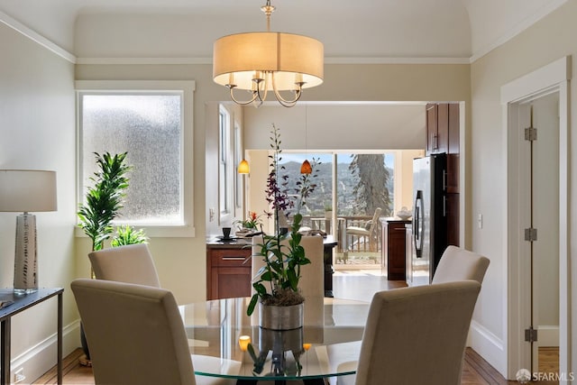 dining space featuring baseboards, a notable chandelier, a healthy amount of sunlight, and wood finished floors