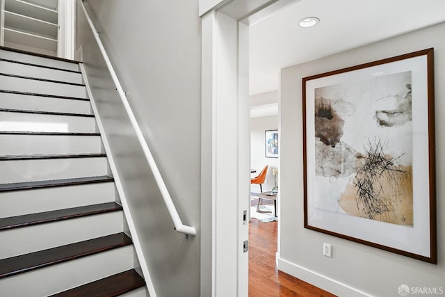 stairway with wood finished floors, baseboards, and recessed lighting