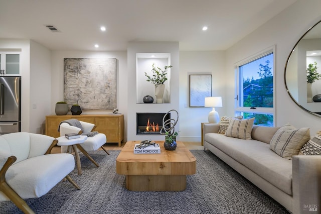 living room with recessed lighting, visible vents, a lit fireplace, and baseboards