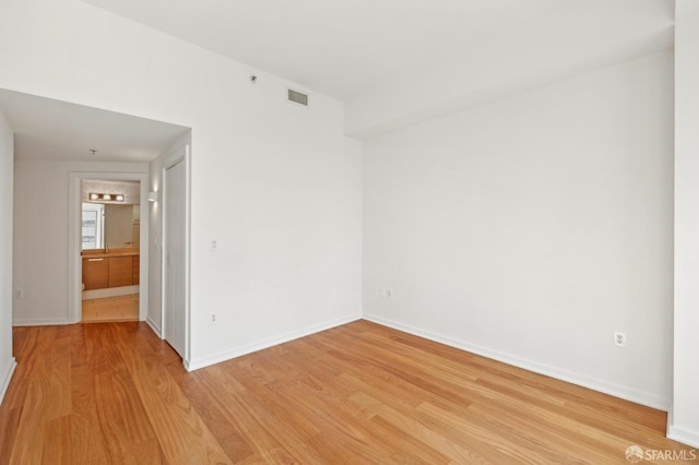 unfurnished room featuring light wood-type flooring, baseboards, and visible vents