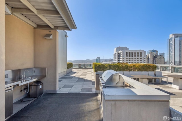 view of patio / terrace featuring a city view, a sink, exterior kitchen, and area for grilling