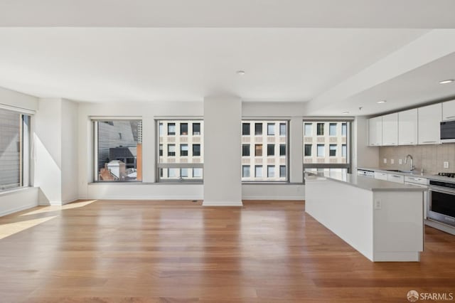 kitchen featuring light wood-style flooring, a sink, a center island, white cabinets, and stainless steel oven