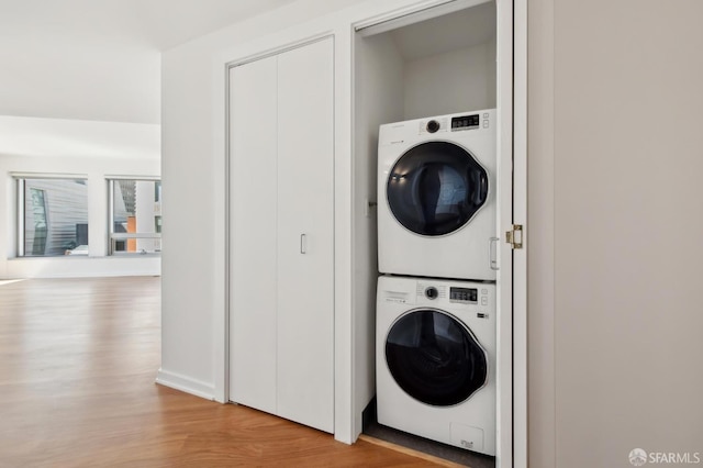 washroom featuring laundry area, stacked washer / drying machine, and wood finished floors