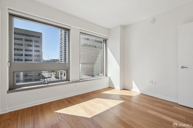 spare room with a city view, wood finished floors, and baseboards