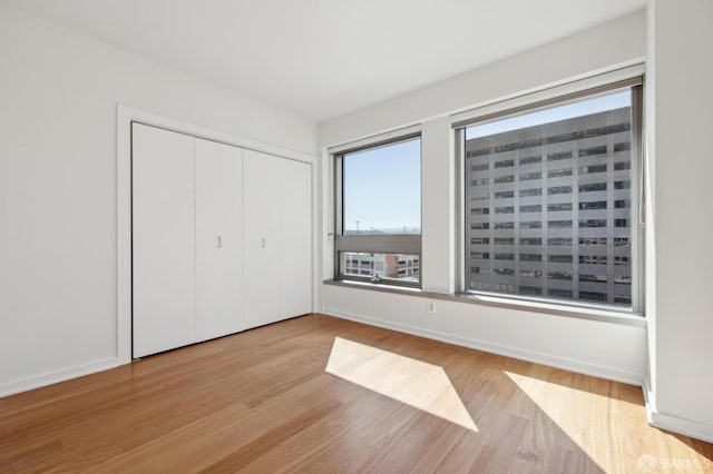 unfurnished bedroom with a closet, baseboards, and wood finished floors