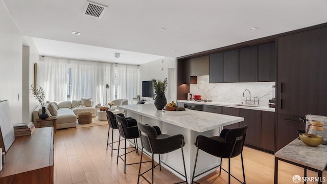 kitchen featuring decorative backsplash, sink, a kitchen breakfast bar, and a center island