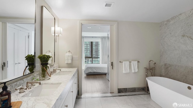 bathroom featuring a tub to relax in, vanity, and tile patterned floors