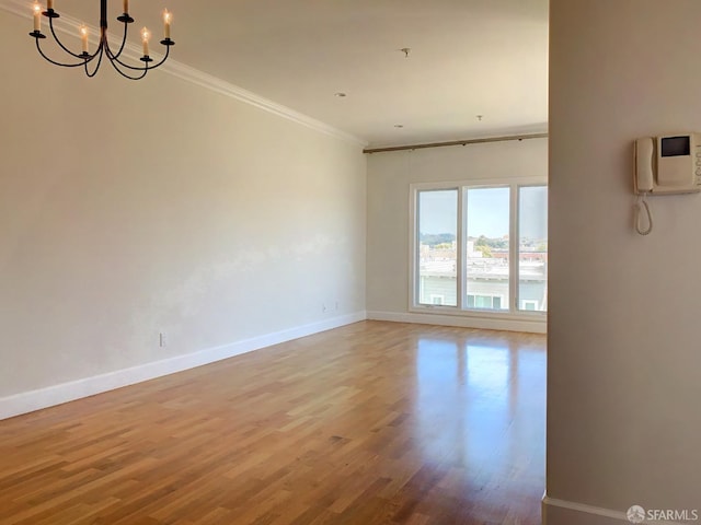 unfurnished room featuring crown molding, a chandelier, and hardwood / wood-style floors