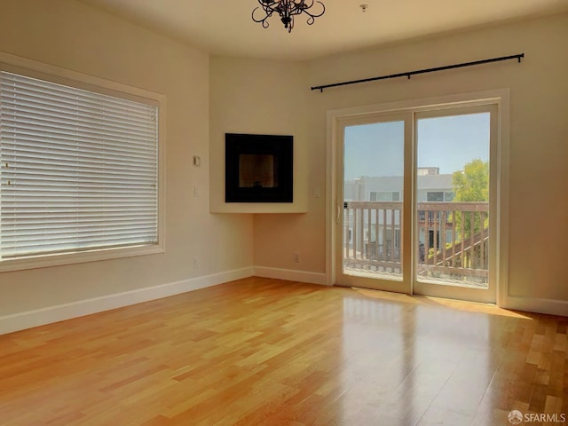 spare room with a notable chandelier and light hardwood / wood-style flooring