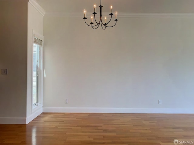 spare room featuring a chandelier, light hardwood / wood-style floors, and ornamental molding