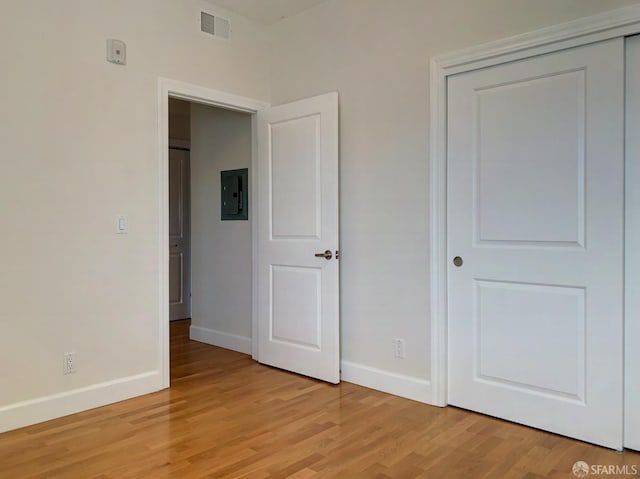 unfurnished bedroom featuring electric panel and light hardwood / wood-style flooring