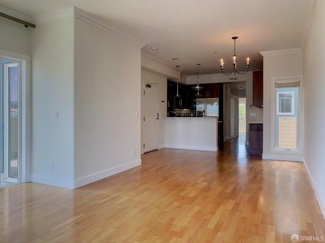 unfurnished living room featuring light wood-type flooring, a chandelier, and ornamental molding