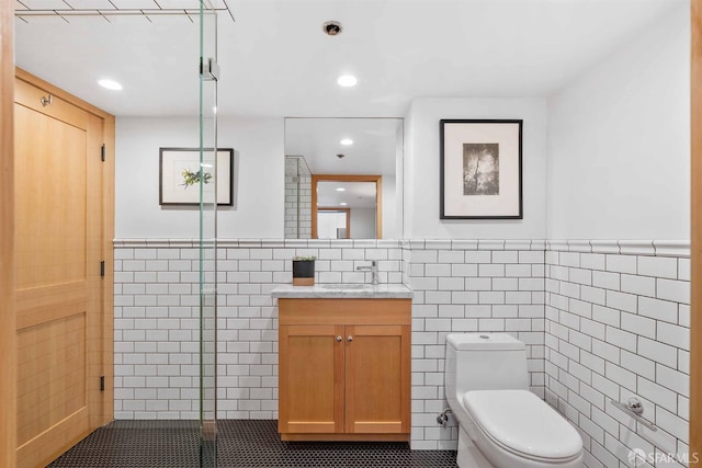 bathroom with tile walls, toilet, vanity, and tile patterned flooring