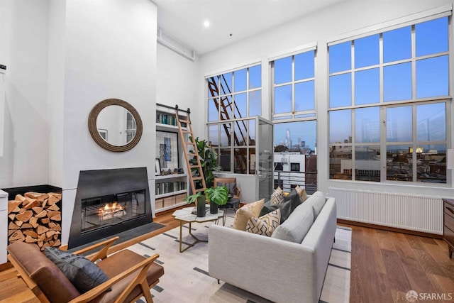 living room with radiator heating unit, hardwood / wood-style flooring, a high ceiling, and a barn door