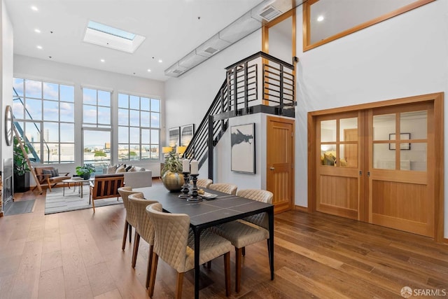 dining area featuring a high ceiling, hardwood / wood-style floors, and a skylight