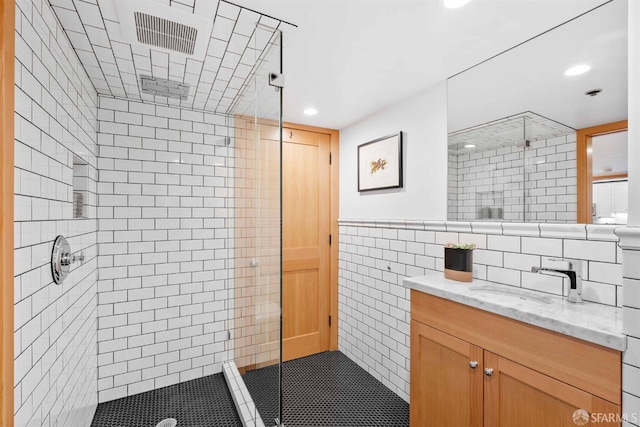 bathroom with tiled shower, tile walls, and vanity