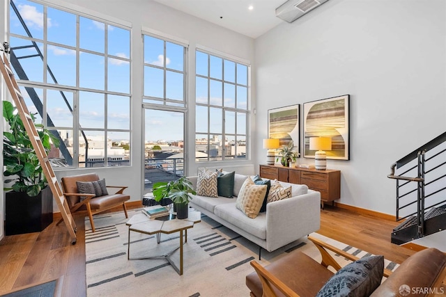 living room with light hardwood / wood-style floors and a towering ceiling