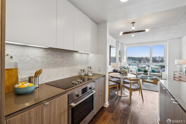 kitchen featuring dark wood-style floors, white cabinetry, stainless steel oven, black electric stovetop, and modern cabinets