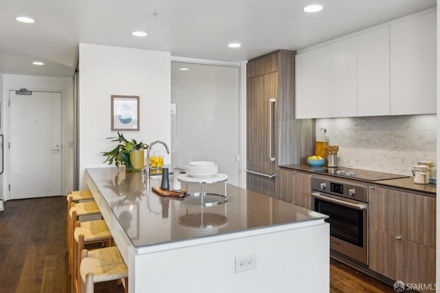 kitchen featuring a breakfast bar area, modern cabinets, oven, and black electric cooktop