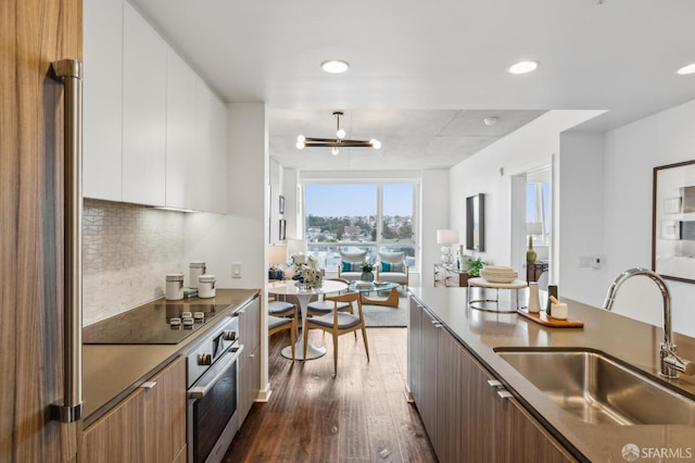 kitchen featuring oven, decorative backsplash, a sink, modern cabinets, and open floor plan