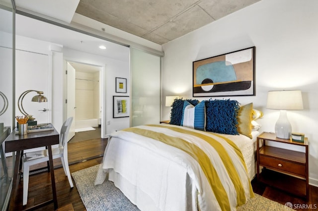 bedroom with ensuite bath and wood finished floors