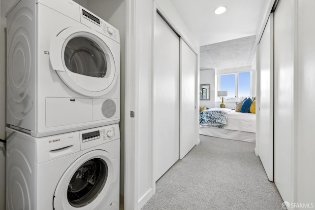 washroom with light carpet, laundry area, and stacked washing maching and dryer