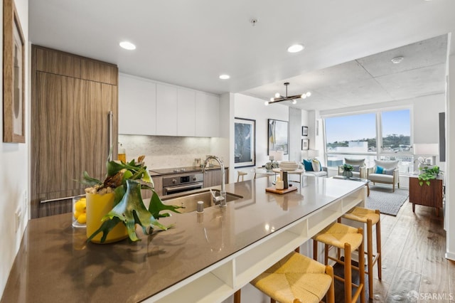 kitchen with light wood finished floors, a breakfast bar area, a peninsula, modern cabinets, and a sink