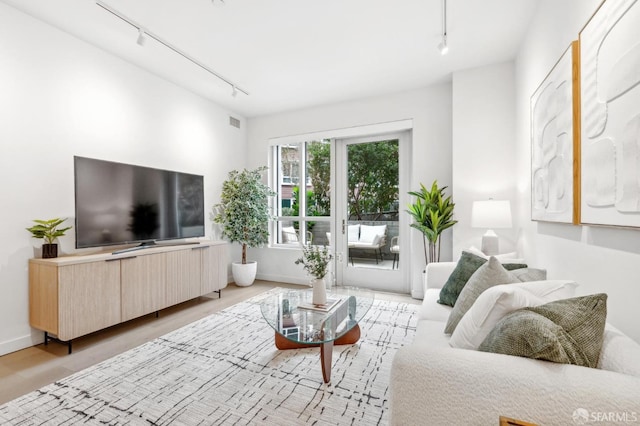 living area featuring visible vents, light wood-style flooring, and track lighting