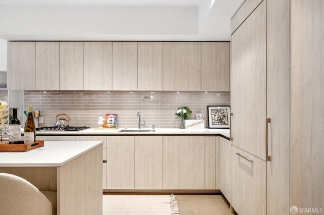 kitchen featuring modern cabinets, light brown cabinets, stainless steel gas cooktop, and a sink