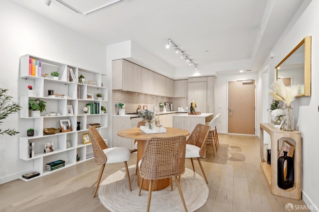 dining area featuring track lighting, light wood-type flooring, and baseboards