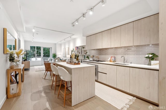 kitchen featuring a center island, light brown cabinets, a sink, and modern cabinets