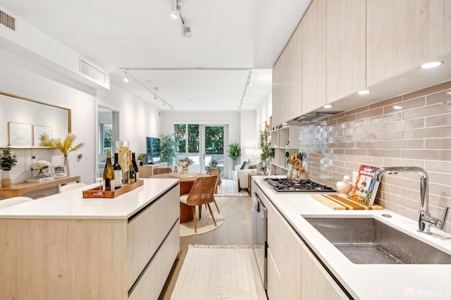 kitchen with modern cabinets, open floor plan, a sink, stainless steel gas cooktop, and backsplash