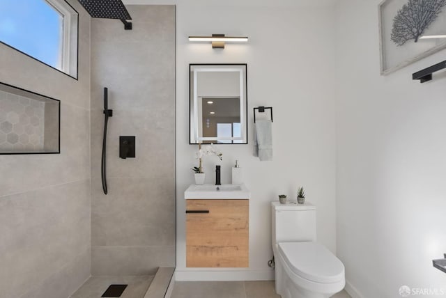 bathroom featuring tile patterned flooring, a tile shower, vanity, and toilet